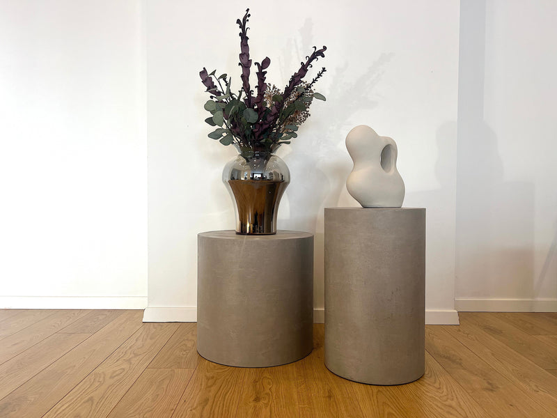 Noční a odkládací stolky z mikrobetonu v moderním interiéru, s vázou a sochou jako dekorací. Stolky s minimalistickým designem, ideální pro stylovou a funkční domácí výzdobu.