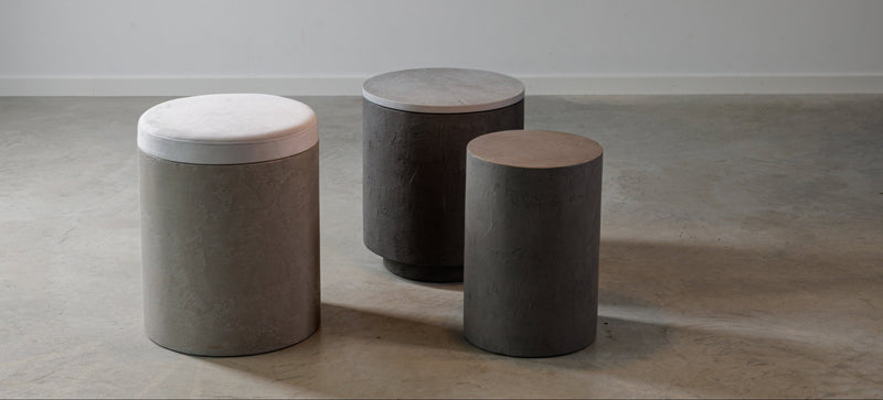 Odkládací a noční stolky z mikrobetonu s minimalistickým designem, vyráběné v Evropě, zobrazené v moderním interiéru. Stolky v různých povrchových úpravách a velikostech, ideální pro funkční a stylovou domácí dekoraci.