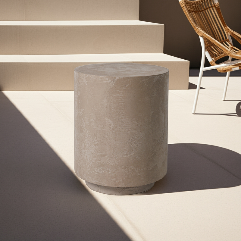 Noční stolek z mikrobetonu v šedé barvě, umístěný na moderní terase. Minimalistický design vhodný pro venkovní i vnitřní prostory, doplněný přírodními materiály.