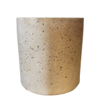 Jednoduchá betonová svíčka na stole, obklopená minimalistickými dekoracemi a pokojovými rostlinami.